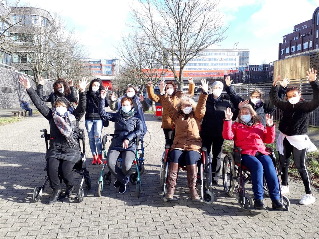 Jubelnde Frauengruppe draußen. Einige sitzen im Rollstuhl.