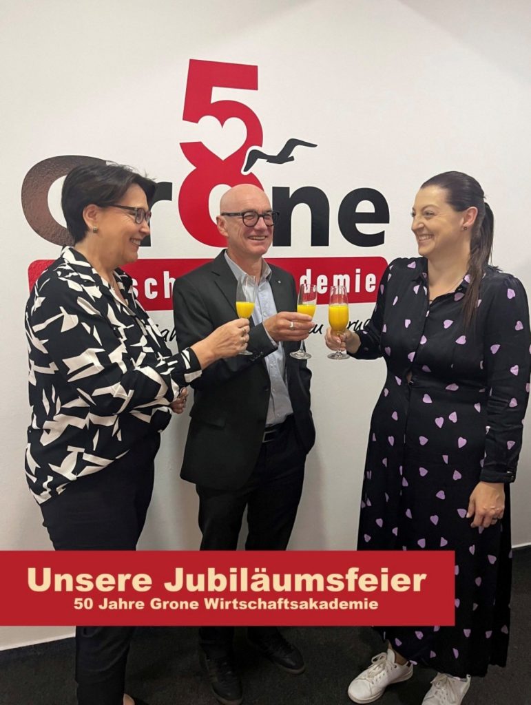 Das Foto zeigt drei leitende Mitarbeitende der Grone Wirtschaftsakademie glücklich beim Anstoßen,