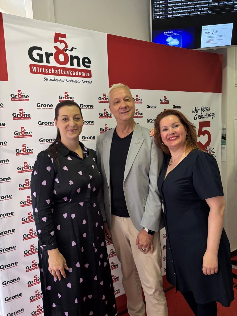 Mitarbeitende der Grone Wirtschaftsakademie und Matthias Geist vom WDTU e.V. posieren vor der Pressewand für ein Foto.